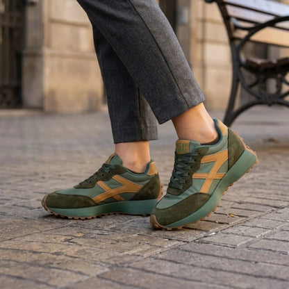 Green and tan trainers worn with grey cropped trousers on a cobbled street 12