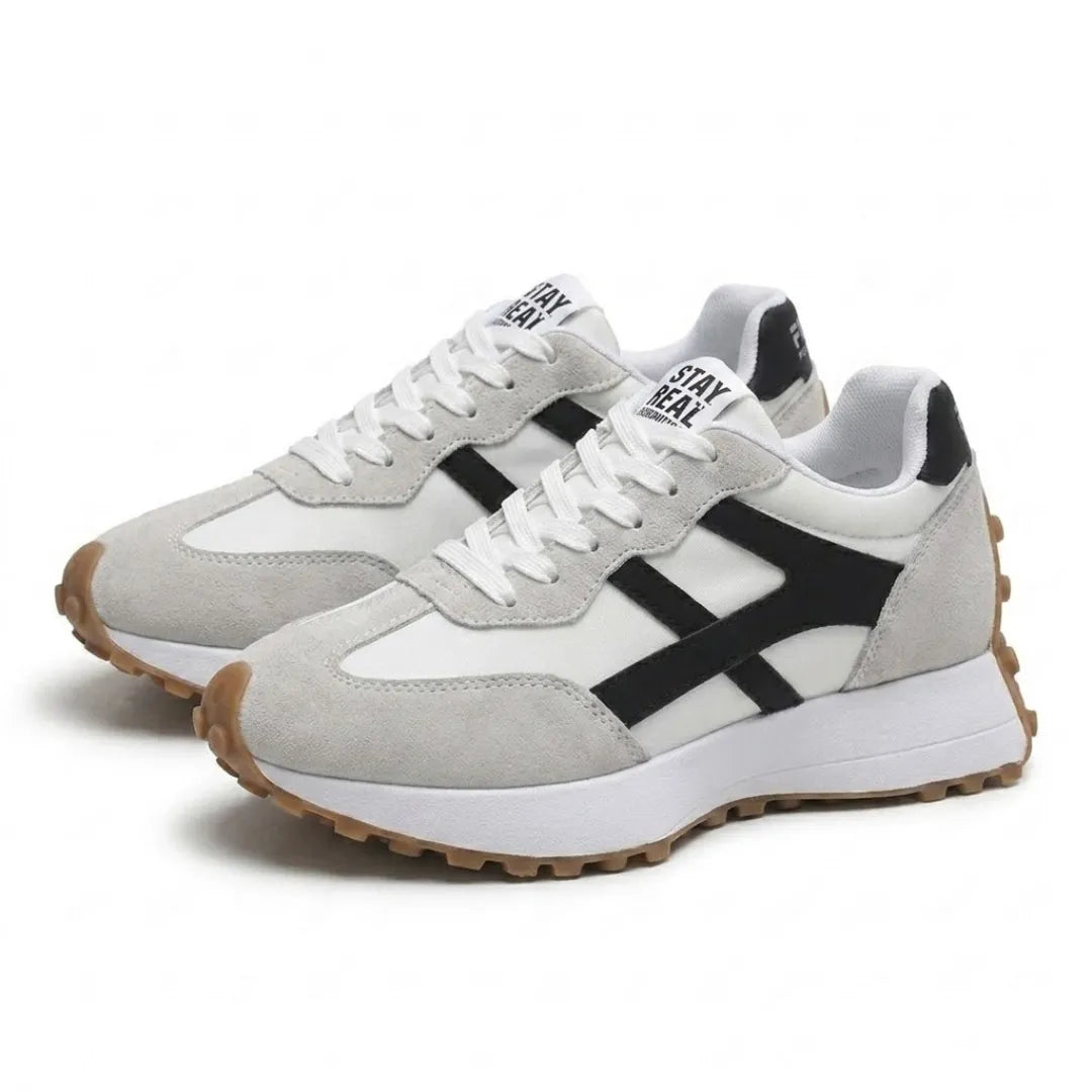 Pair of grey and white lace-up trainers with black side stripes, angled three-quarter view on plain background 23