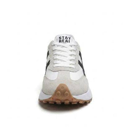 Front view of a trainer showing white laces, grey suede toe cap and studded gum-coloured sole 24