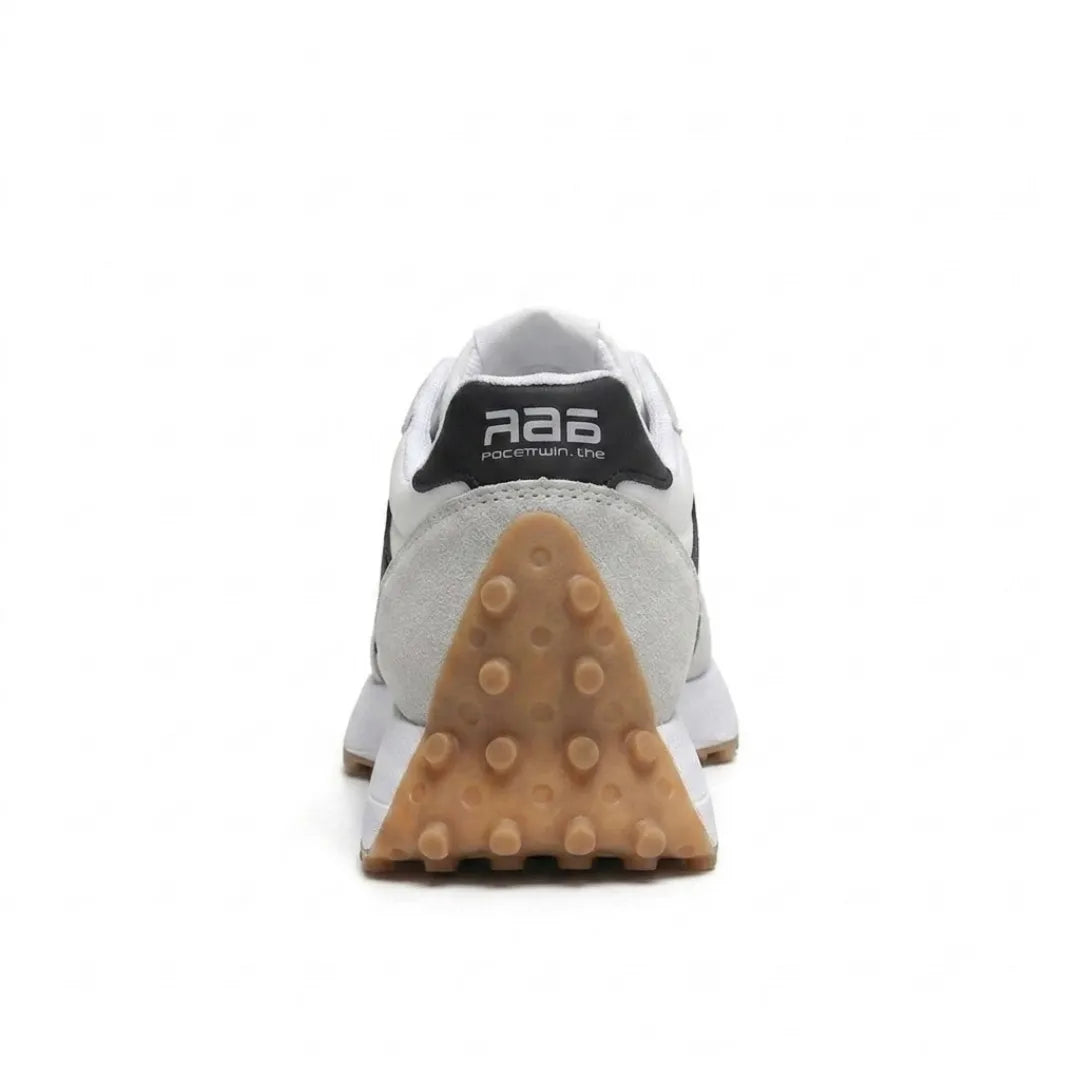 Rear view of a trainer showing the black heel tab and triangular studded gum-coloured heel 25