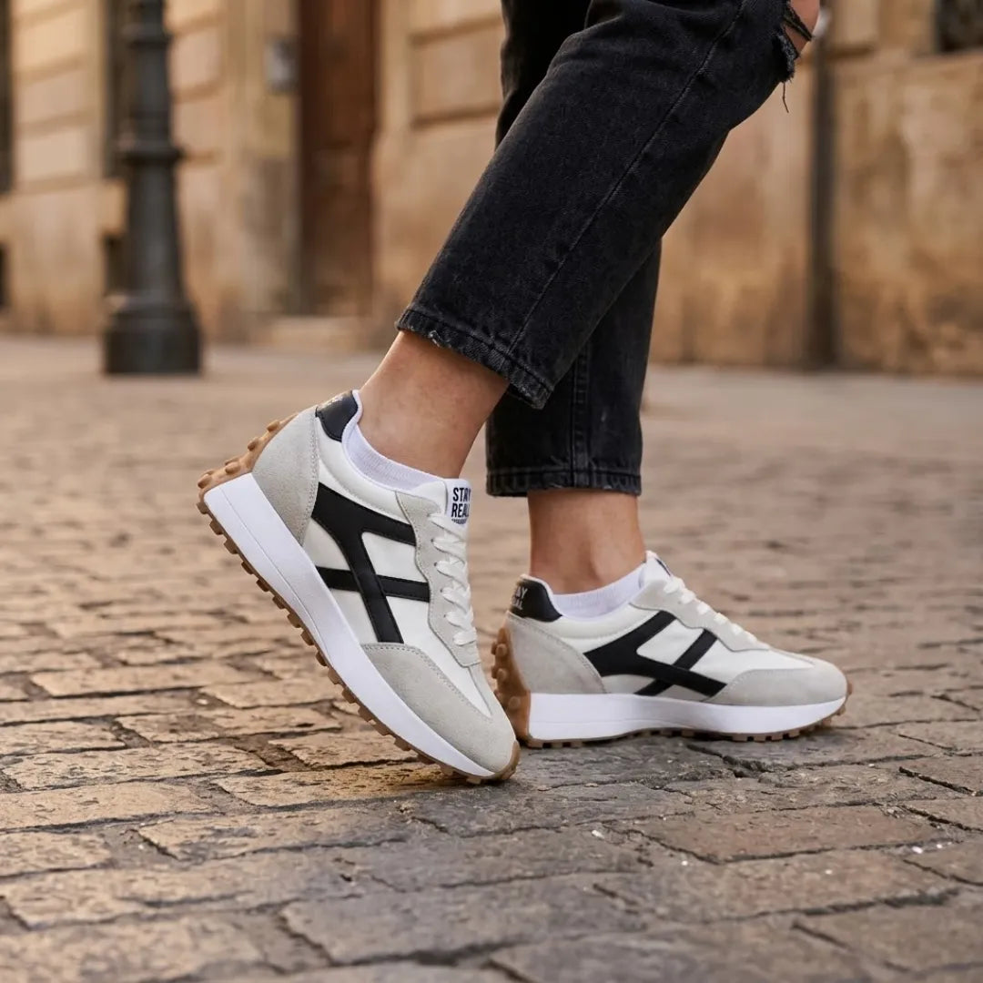 Pair of trainers worn with black jeans and white socks on a cobbled street 22