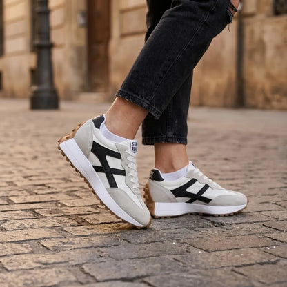 Pair of trainers worn with black jeans and white socks on a cobbled street 22