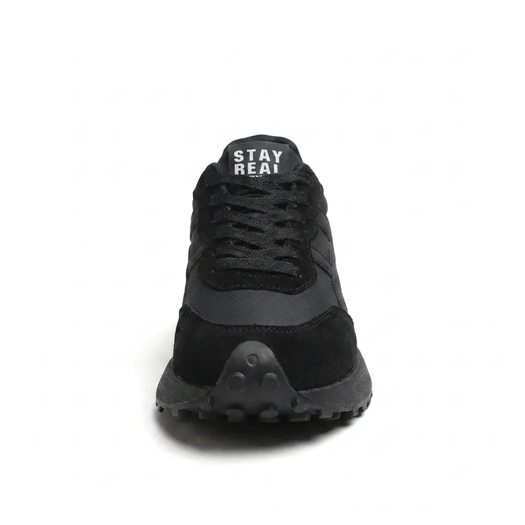 Front view of the all-black trainer showing laces, tongue label and studded toe sole 9