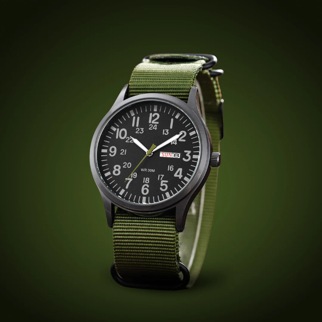 Angled view of the black-dialled watch with olive green woven strap and black rings against a dark green background. 4
