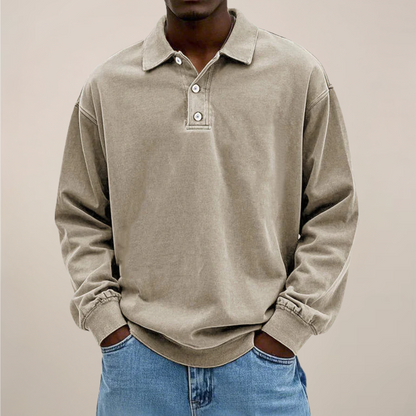 Front view of the polo in washed sandy beige, worn by a model with hands in the pockets of blue jeans. 6