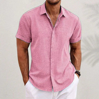 Pink textured short-sleeve shirt with cuffed sleeves and a spread collar, worn by a model with white trousers. 8