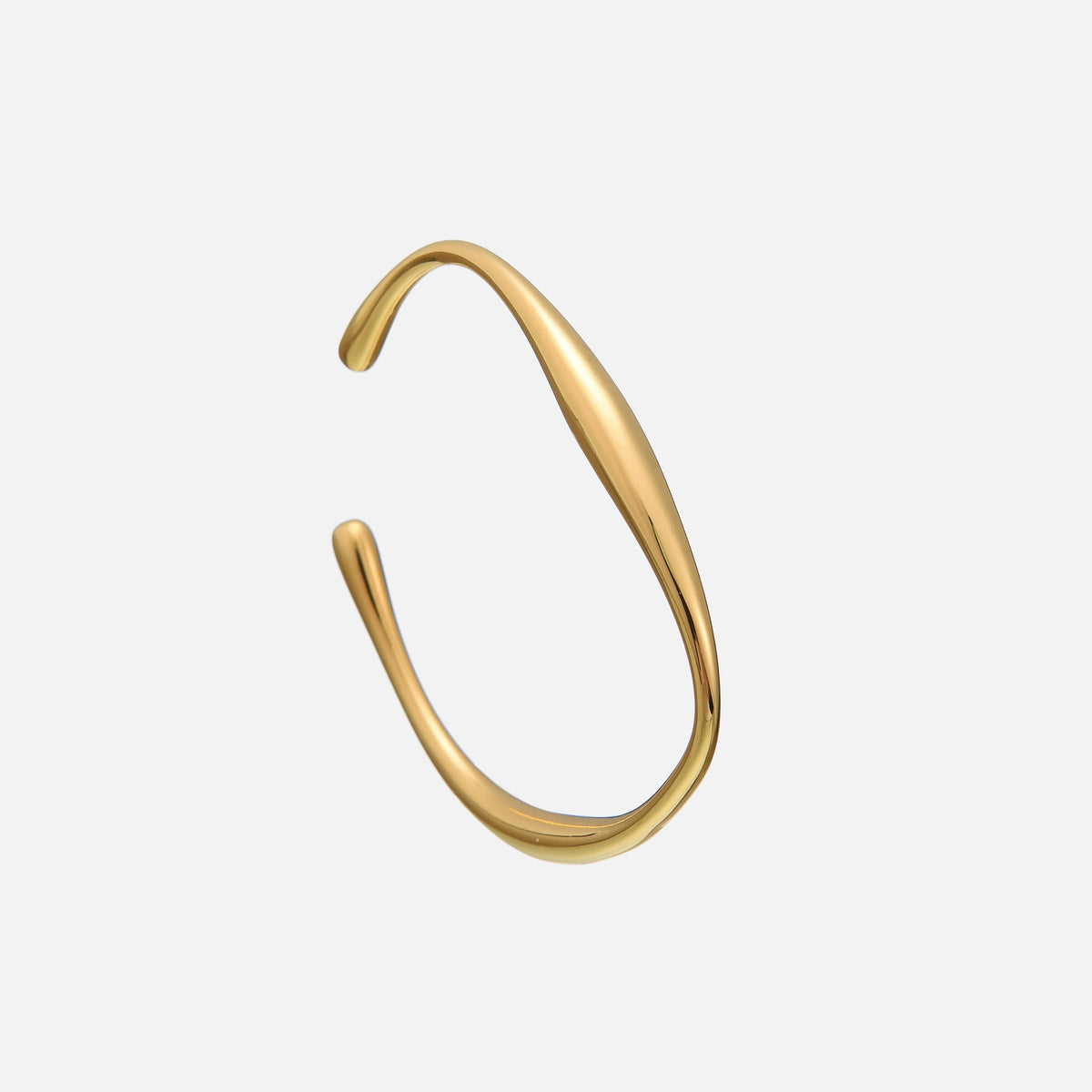 Open gold-coloured cuff bracelet with a smooth, flowing wave shape and rounded teardrop ends, shown at an angle on a plain grey background. 1