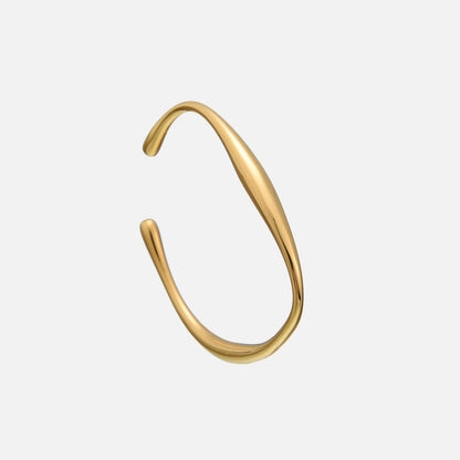 Open gold-coloured cuff bracelet with a smooth, flowing wave shape and rounded teardrop ends, shown at an angle on a plain grey background. 1