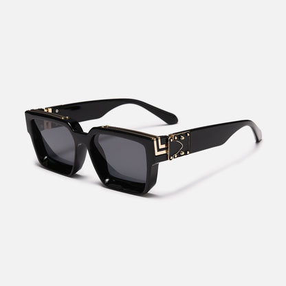 Glossy black square sunglasses with grey lenses and gold-coloured metal trim on the brow and hinge plate, three-quarter view. 8