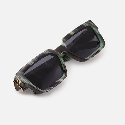 Folded sunglasses with a green and black streaked frame and gold-coloured hinge, photographed from above. 16