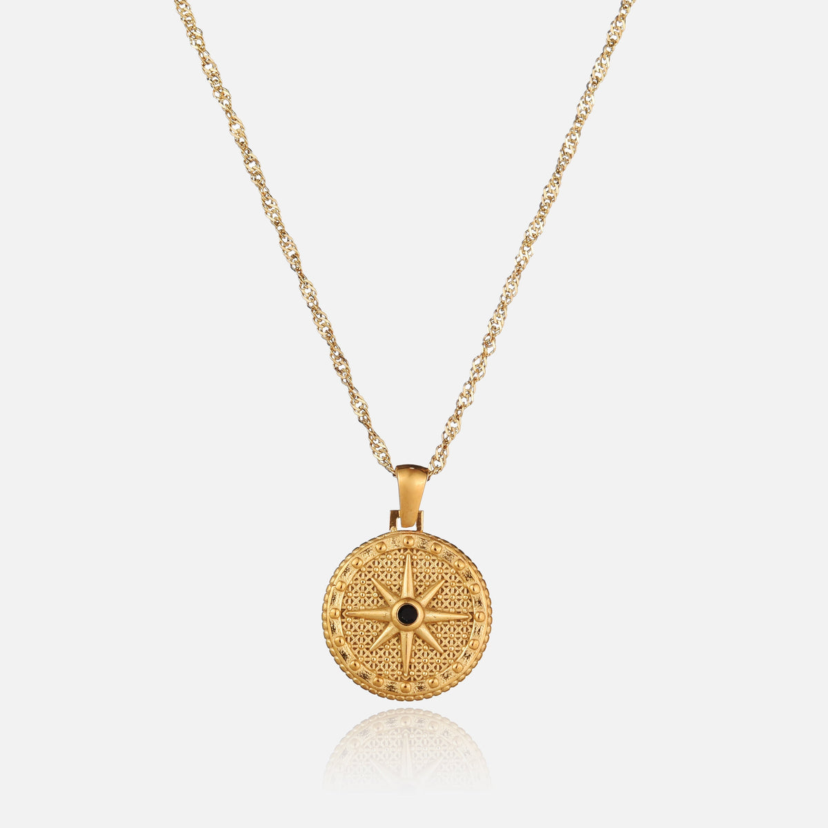 Round gold pendant with an eight-pointed star and black stone, hanging on a twisted chain, front view 1