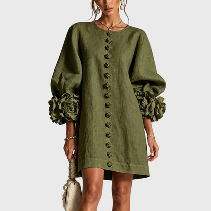 Front view of the dress in olive green on a model, showing the floral buttons and large rosette cuffs. 2