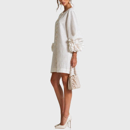Side view of the white dress on a model with cream heels and a small bag, showing the puff sleeve and cuff rosette. 8