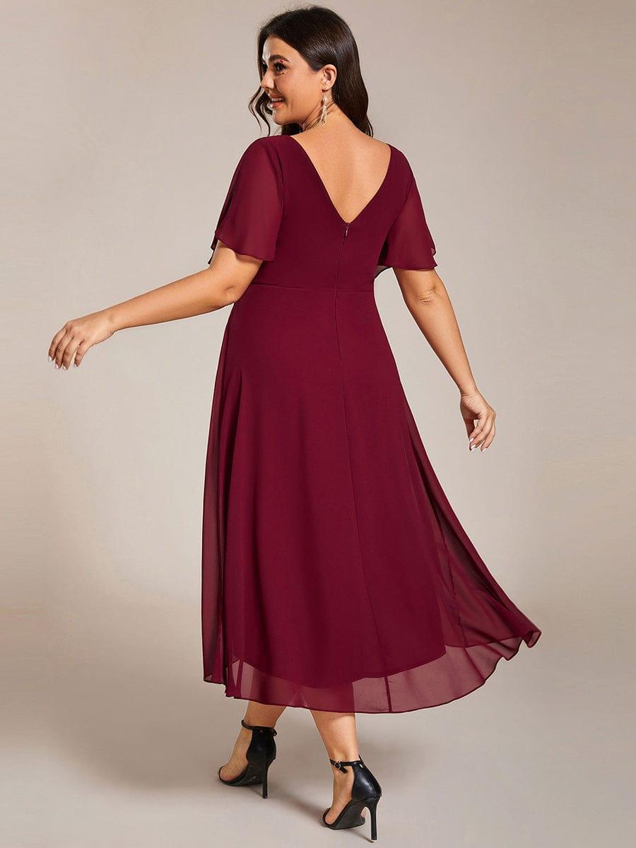 Back view in burgundy showing the V-shaped back, centre zip and sheer layered high-low skirt on a plus-size model. 50