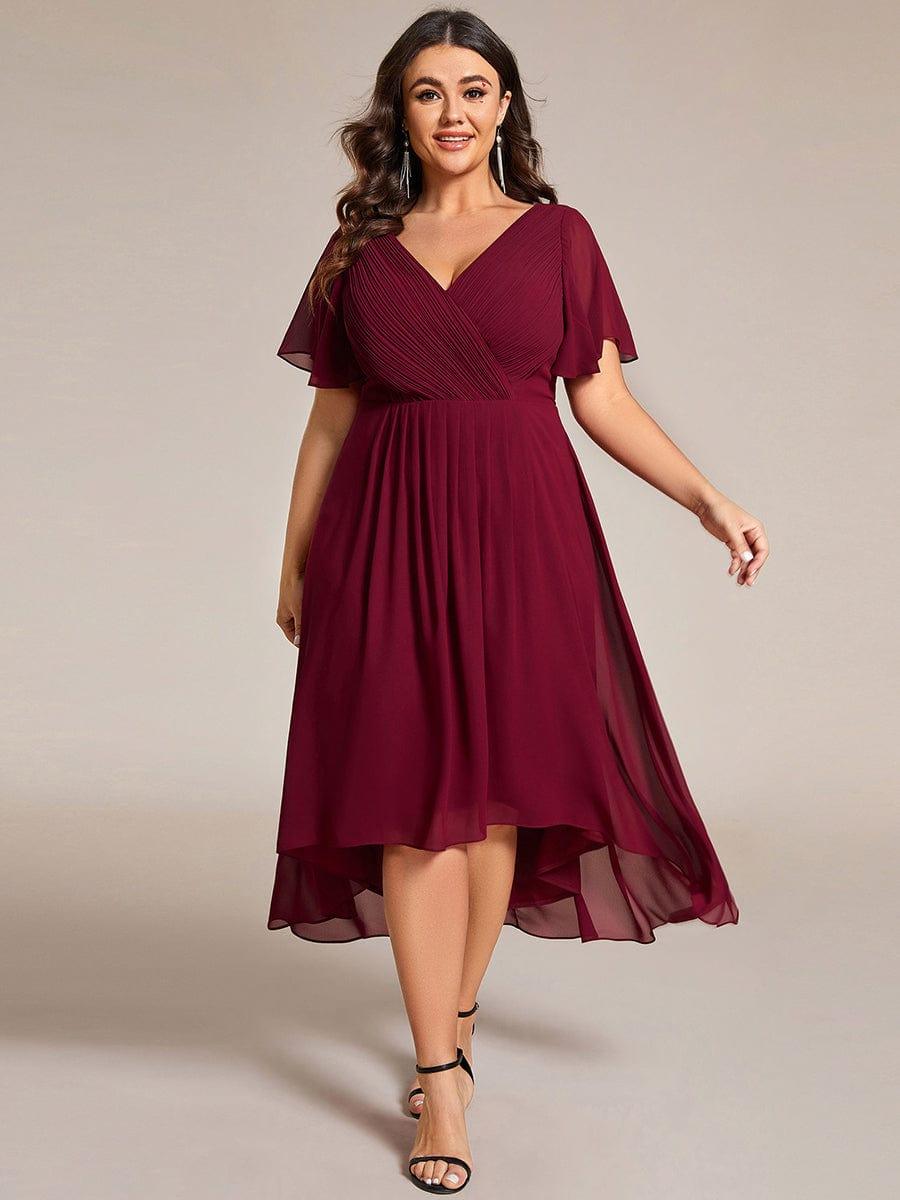 Plus-size model in burgundy pleated chiffon dress with flutter sleeves, black heels and long tassel earrings. 49