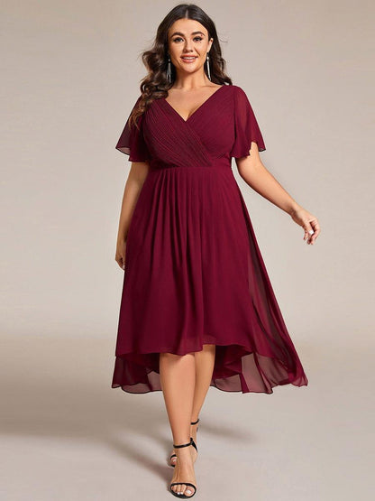Plus-size model in burgundy pleated chiffon dress with flutter sleeves, black heels and long tassel earrings. 49