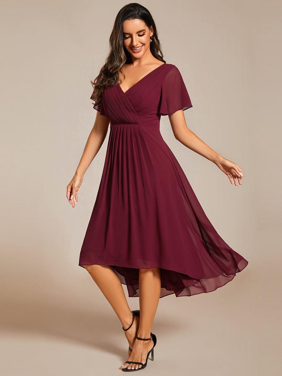 Model in burgundy chiffon dress with black strappy heels, looking down and swaying to show the high-low hem. 47