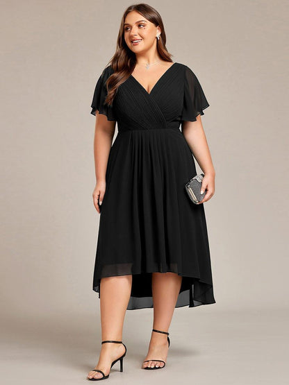 Plus-size model in the black dress holding a small embellished clutch, standing in black strappy heels. 30