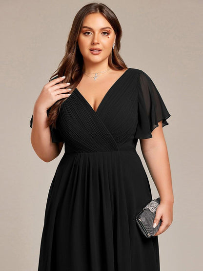 Close-up of the black dress's pleated wrap bodice on a plus-size model holding a sparkly clutch bag. 28
