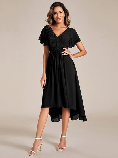 Black chiffon dress with pleated wrap bodice and flutter sleeves, worn by a smiling model with one hand on her hip. 21