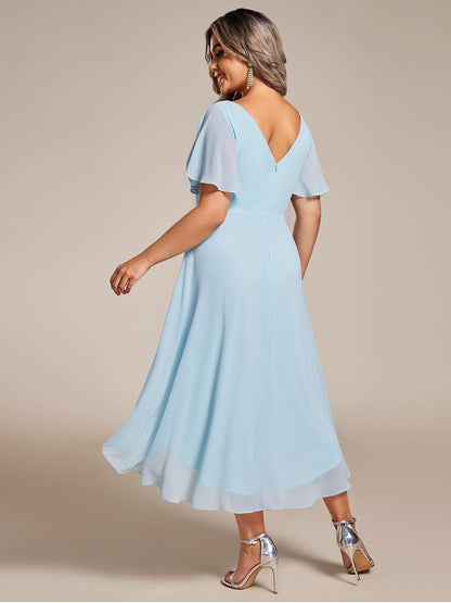 Back of the light blue dress on a plus-size model, showing the low V back, zip and layered chiffon hem. 90