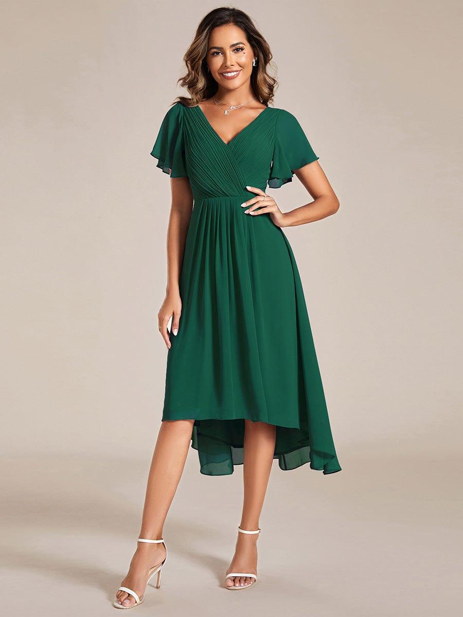 Front view of the dark green chiffon dress on a model with hand on hip, pleated V-neck and flutter sleeves. 10