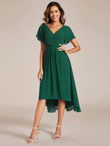 Front view of the dark green chiffon dress on a model with hand on hip, pleated V-neck and flutter sleeves. 10