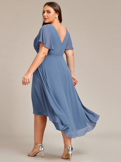 Back view in dusty blue showing the V-shaped back, centre zip and flowing high-low chiffon skirt on a plus-size model. 42