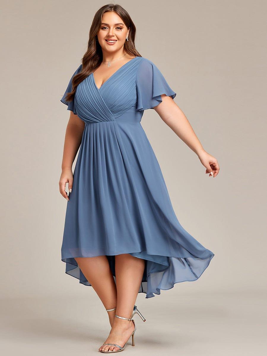 Plus-size model in dusty blue chiffon dress twirling, showing the pleated bodice and uneven high-low hemline. 45