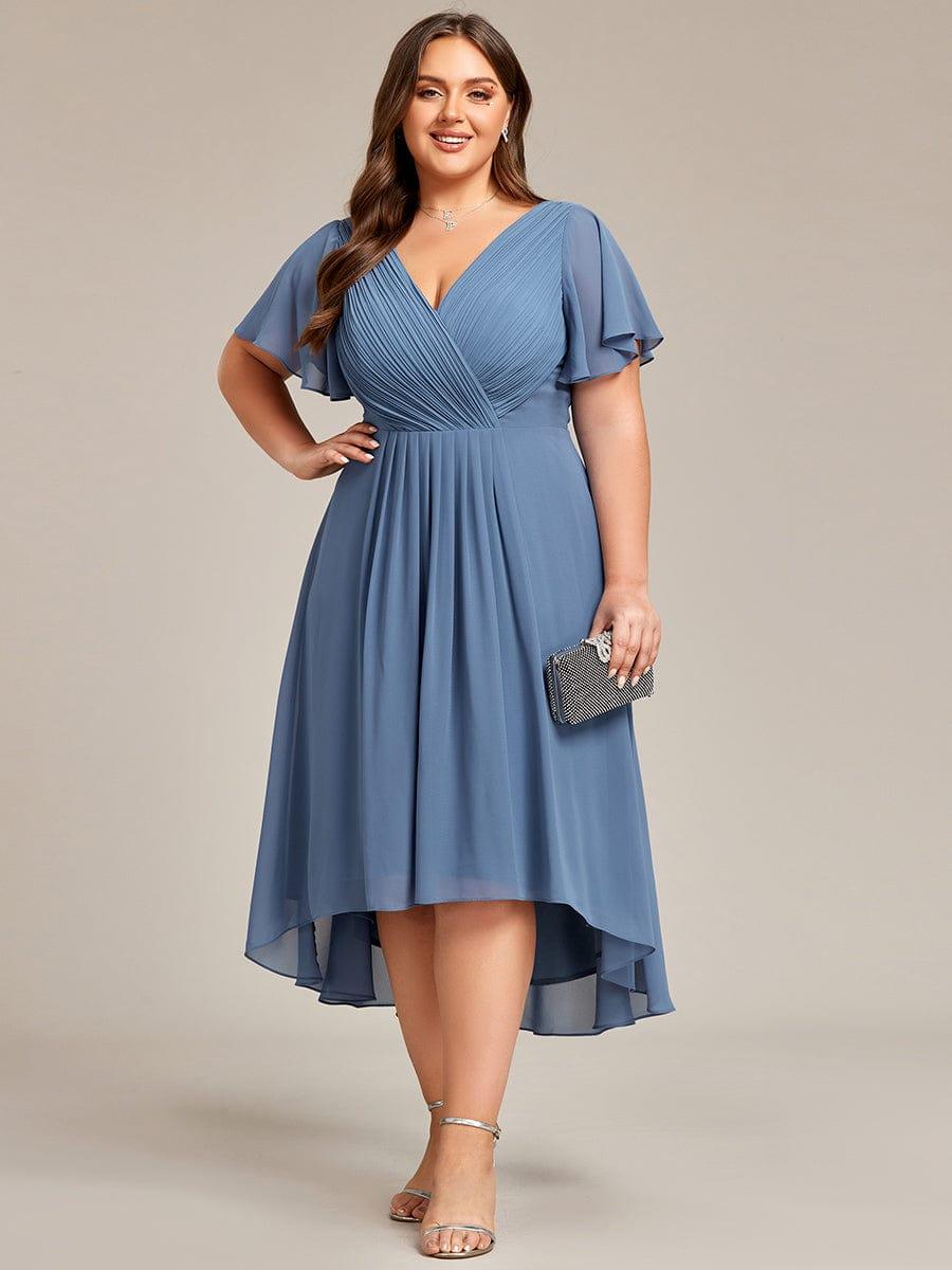 Plus-size model in dusty blue high-low chiffon dress, hand on hip, holding a black sparkly clutch. 44
