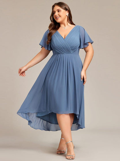 Plus-size model in dusty blue pleated chiffon dress with flutter sleeves, swirling high-low hem and silver heeled sandals. 41