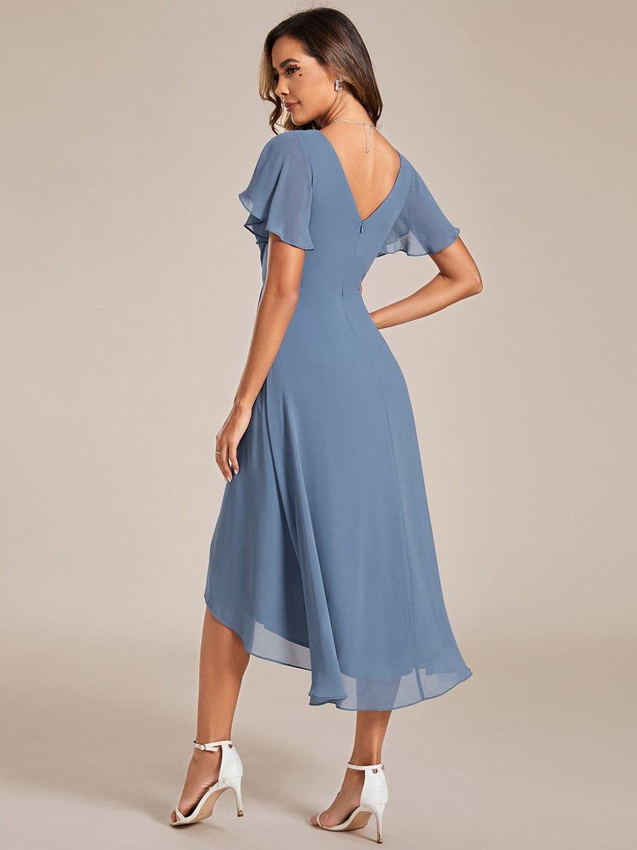 Back view of the dusty blue dress, showing the deep V-back, zip, flutter sleeves and asymmetric high-low hemline. 6
