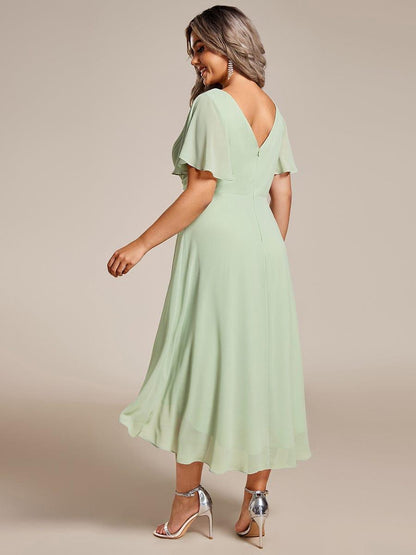 Back of the mint green dress on a plus-size model, showing the deep V back, zip and flowing high-low hem. 82