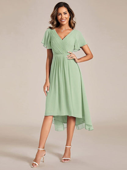 Model in the pale sage green version of the dress, front view with white heeled sandals. 76