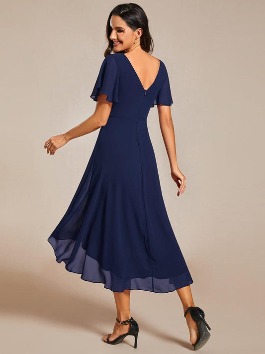 Back view of the navy dress on a model, showing the low V-back, zip, flutter sleeves and sweeping high-low hem. 2