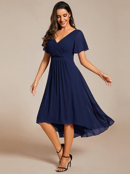 Model in navy chiffon dress with pleated bodice and black strappy heels, swaying to show the high-low hem. 52
