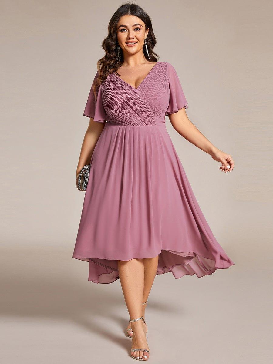 Plus-size model in the dusky pink dress, facing forward with a small clutch, high-low hem swinging. 63