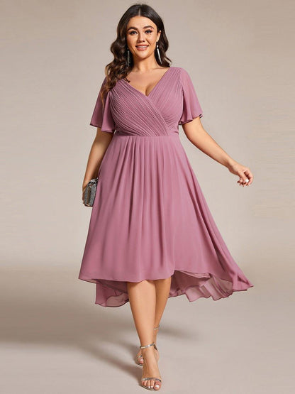 Plus-size model in the dusky pink dress, facing forward with a small clutch, high-low hem swinging. 63