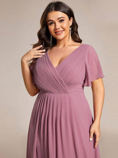 Close-up of the pleated wrap bodice and flutter sleeve on a plus-size model in dusky pink. 65