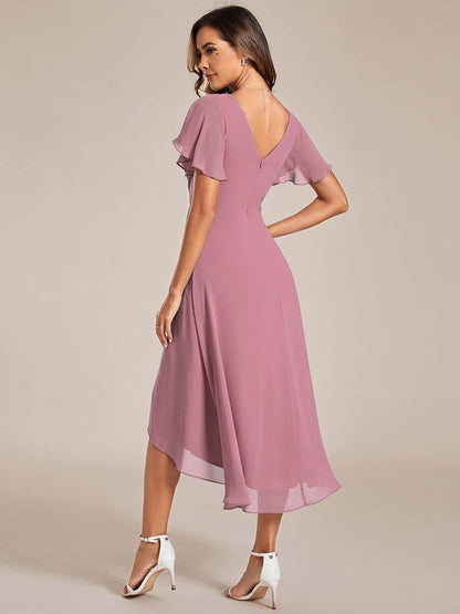 Back view in dusty rose pink showing the V-shaped back, zip and asymmetric high-low chiffon hem with white heels. 59