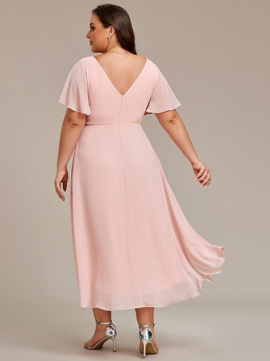 Back view of the pale pink dress on a plus-size model, showing the V back, zip and flowing hem. 32