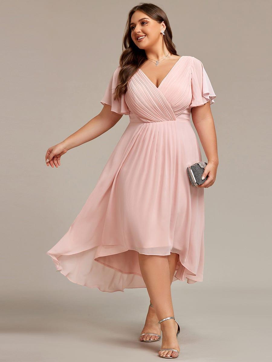 Plus-size model wearing the dress in pale pink, holding a sparkly clutch with silver heels. 31