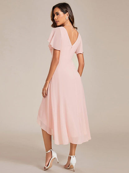 Back view of the pink dress, showing the low V-back, concealed zip, flutter sleeves and asymmetric chiffon hem. 16