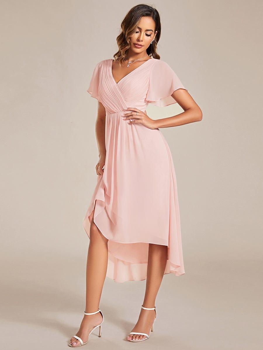 Model in the pink dress lifting the skirt slightly with one hand on hip, showing the layered high-low chiffon hem. 19