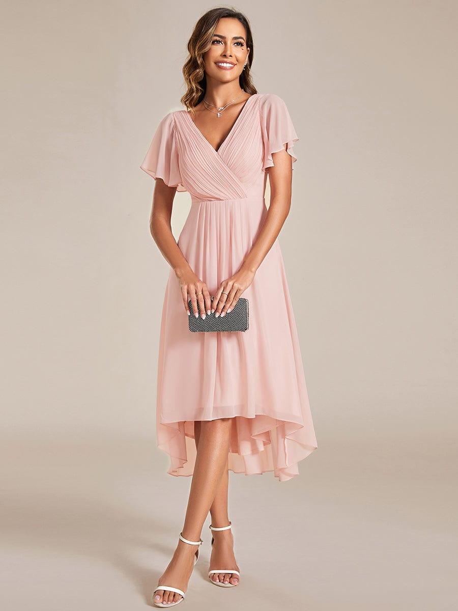 Front view of the pink chiffon dress on a model holding a black beaded clutch with both hands. 15