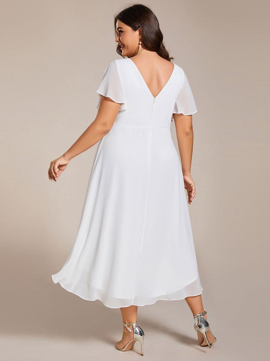 Back view of the white dress on a plus-size model, showing the V-back, zip and layered hem. 74