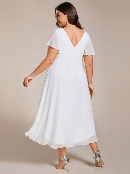 Back view of the white dress on a plus-size model, showing the V-back, zip and layered hem. 74