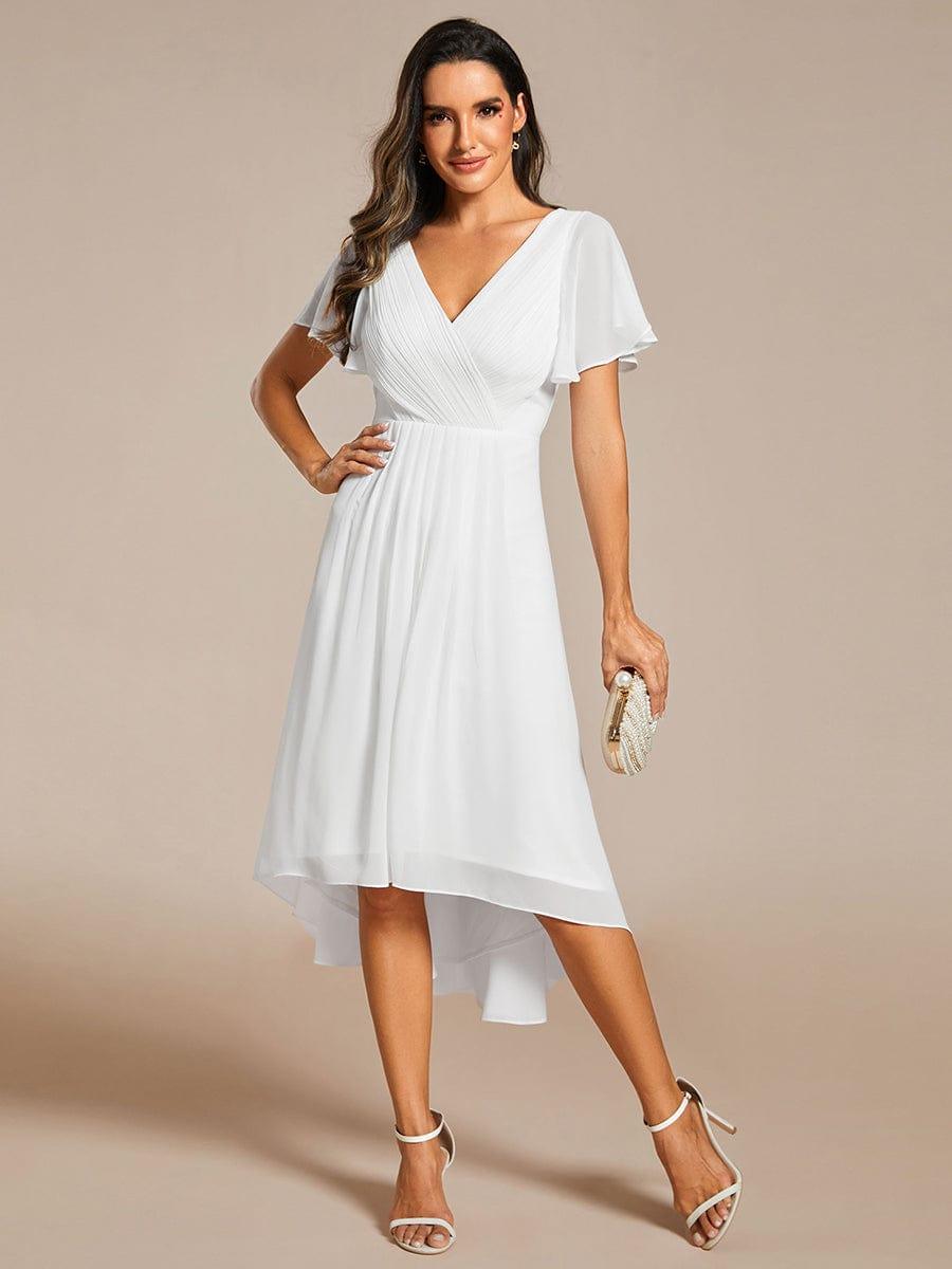 Model in the white dress with one hand on her hip, holding a clutch, full-length front view. 71