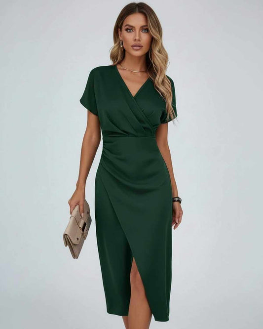 Model wearing the short-sleeved wrap dress in dark green, holding a beige clutch bag 2