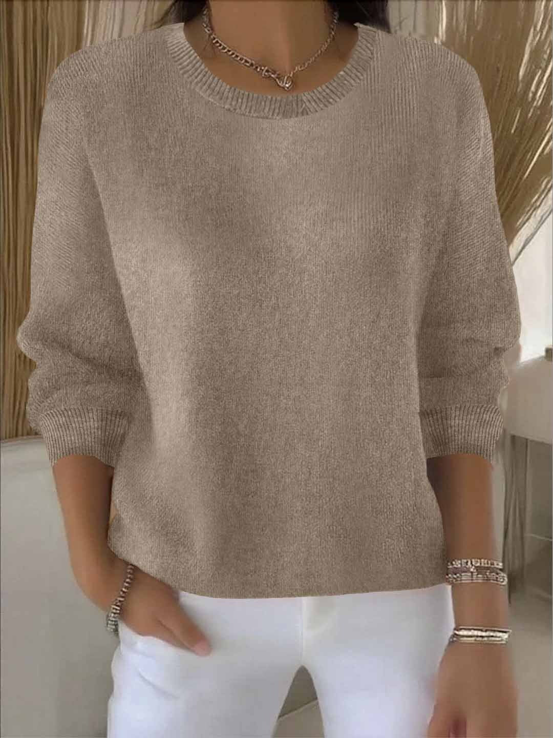 Woman wearing a taupe round-neck knit jumper with ribbed cuffs, styled with white trousers 5
